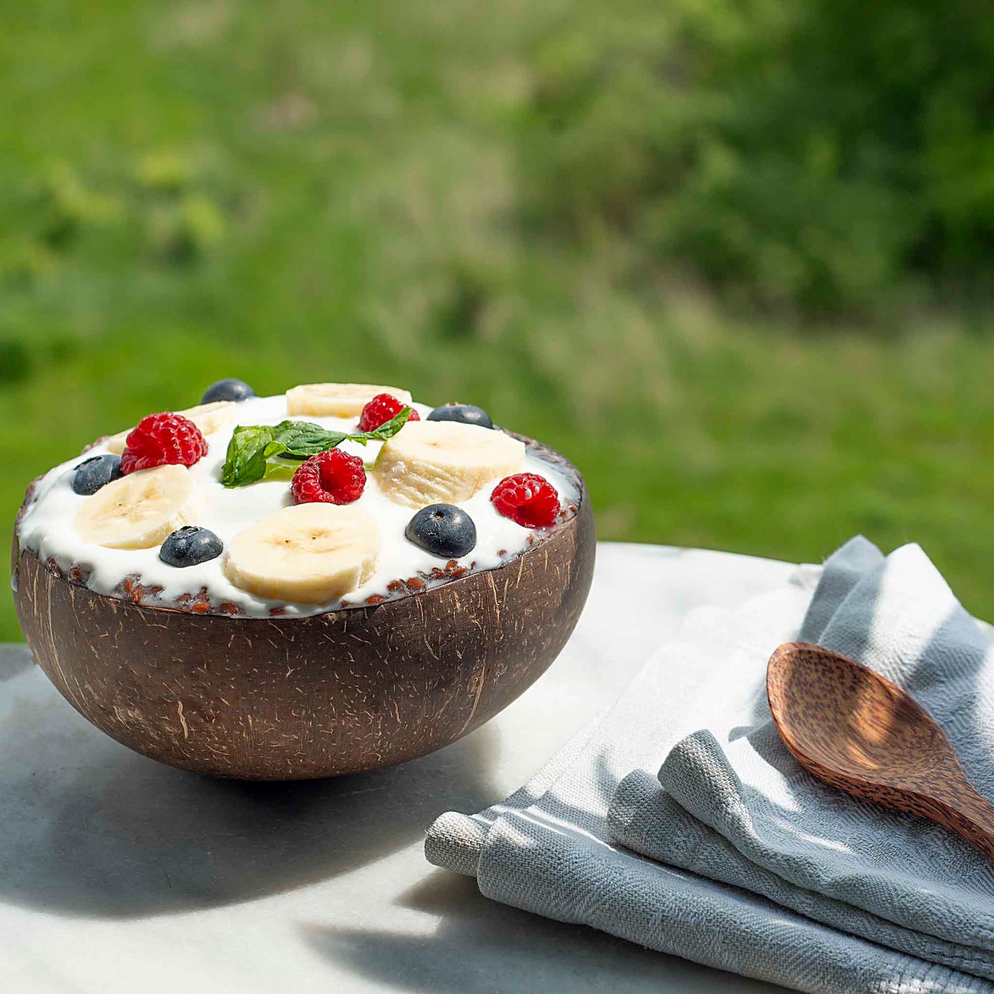 MIDI dydžio kokoso dubenėlis padėtas ant sato su smoothie viduje – aiškiai matomas proporcijos ir tūris.