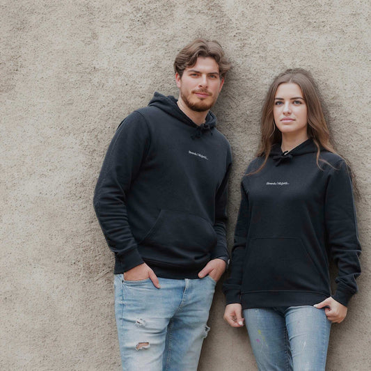 Unisex džemperis „Skrendu i Niujorkà“ ant vyro ir moters modelių prie sienos